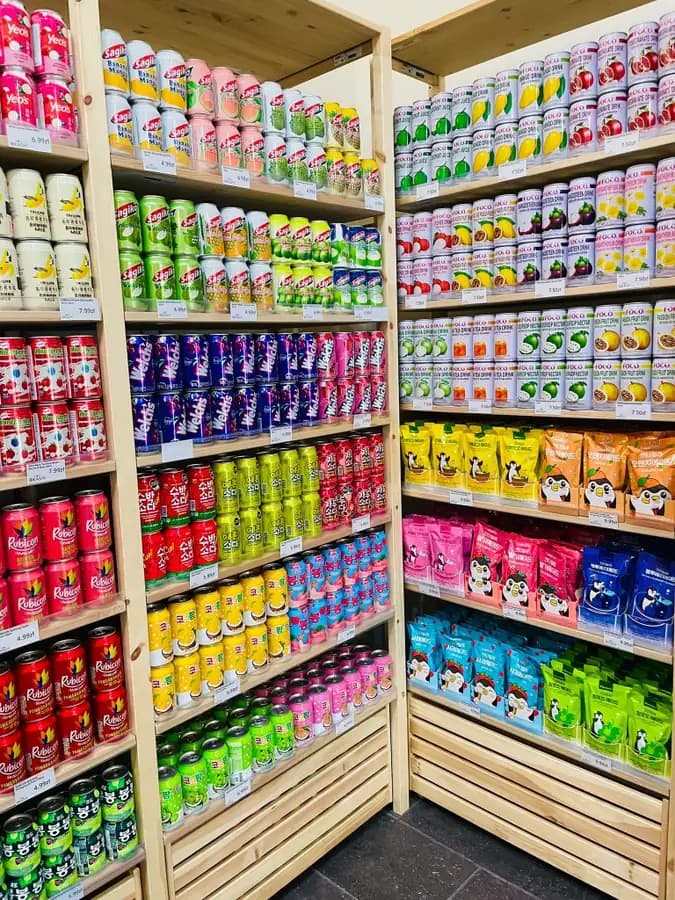 Colourful canned fruit drinks and juice pouches in the OKASHI Group beverage aisle
