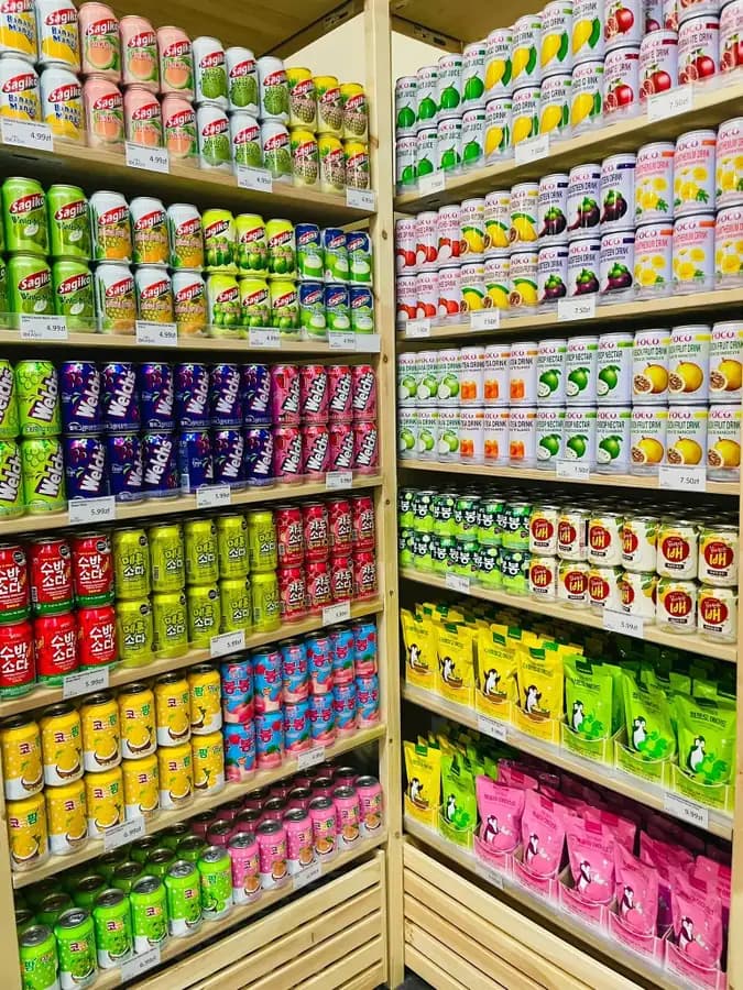 FOCO, Sagiko and Welch’s canned Asian drinks on wooden shelves at OKASHI Group