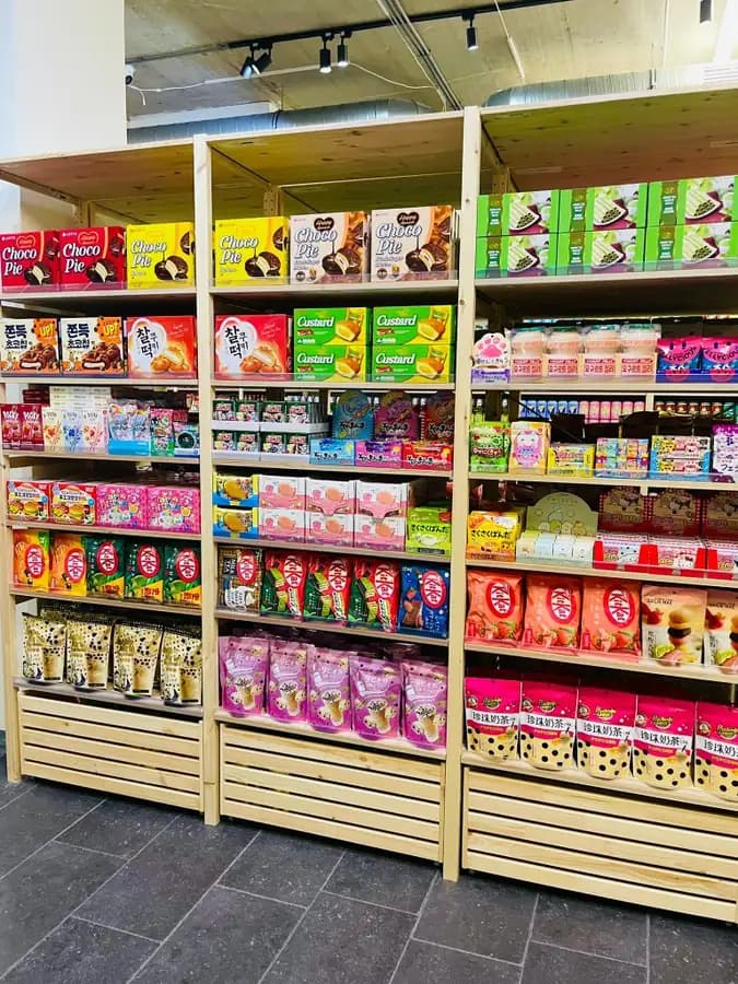 Wooden shelves of Japanese and Korean snacks at OKASHI Wrocław: Choco Pie, Pocky, KitKat and candy